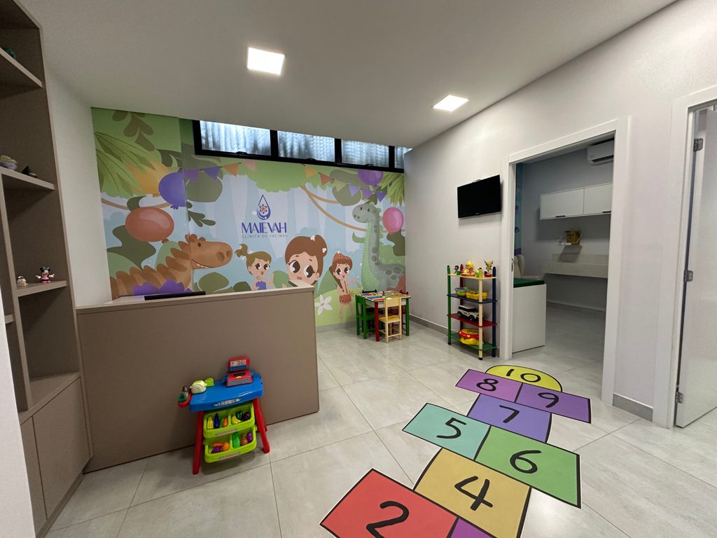 Recepção com amarelinha no piso e sala de aplicação ao fundo