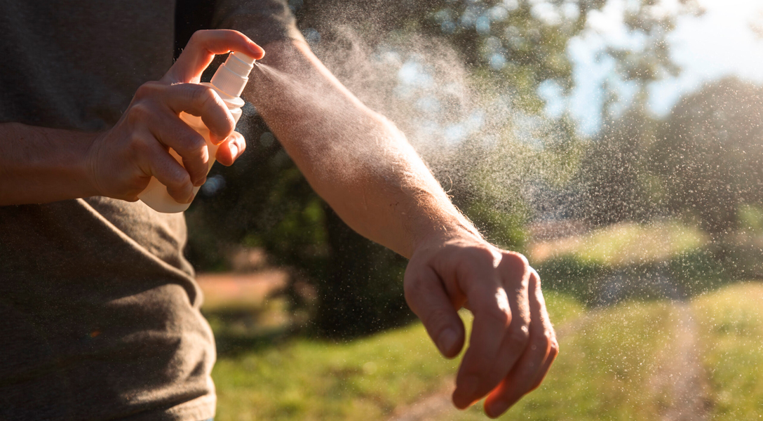 Pessoa aplicando repelente no braço ao ar livre para prevenção da dengue